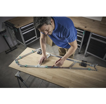 En man använder en konturmall för att överföra en form till en träplanka.