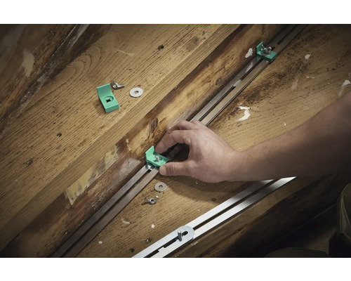 Montering av monteringsvinklar med skruvar och brickor på en metallskena på träunderlag