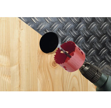 Hålsåg borrar hål i trä med durkplåt i bakgrunden