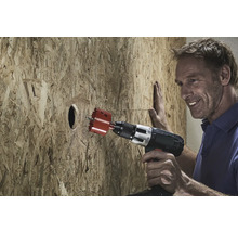 En man borrar ett hål i en träskiva med en hålsåg