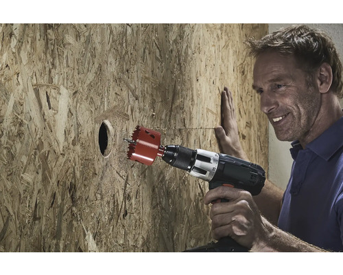 En man borrar ett hål i en träskiva med en hålsåg