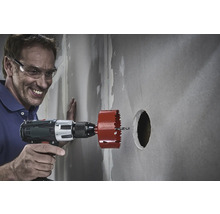 En man borrar ett hål i en vägg med en hålsåg.