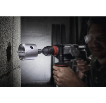 Borrmaskin med hålsåg borrar ett hål i en betongvägg.