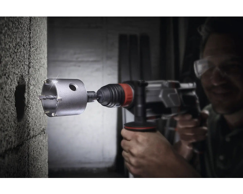 Man borrar ett hål i en vägg med en hålsåg.