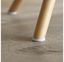 Detaljvy av ett stolsben med golvskydd på ett trägolv.