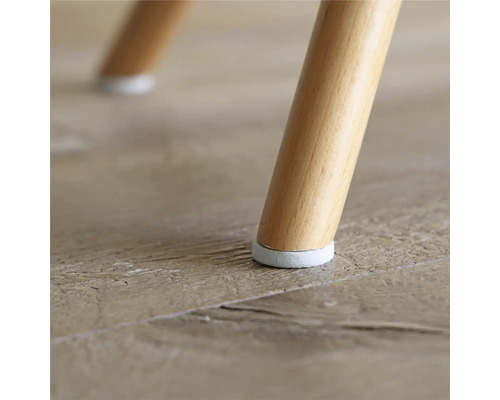 Detaljvy av ett stolsben med golvskydd på ett trägolv.