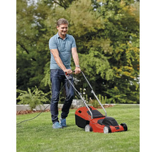 En man klipper gräsmattan med en elektrisk gräsklippare.