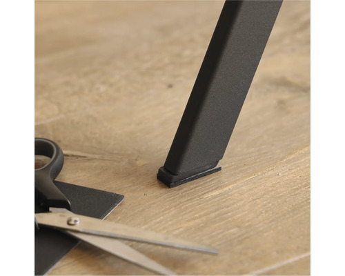 Möbelglid under ett bordsben och en sax för att klippa till rätt storlek