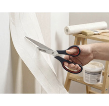 En person skär tapet med en sax av märket Rautner