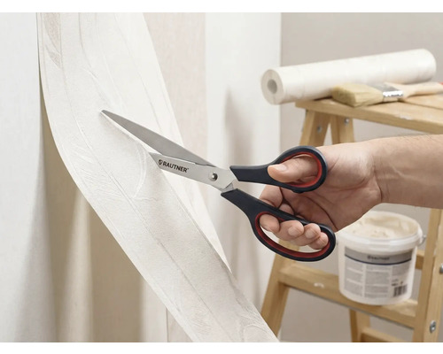 En person skär tapet med en sax av märket Rautner