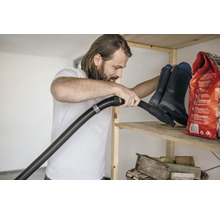 Man dammsuger hylla med gummistövlar och säck