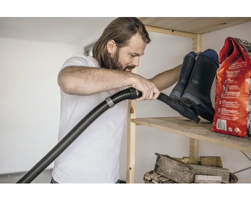 Man dammsuger hylla med gummistövlar och säck