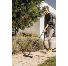 Kvinna dammsuger löv i trädgården med en våt- och torrdammsugare