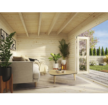 Interiörbild av ett trädgårdshus i trä med soffa, växter och en öppen dörr till trädgården