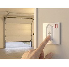 Hand manövrerar garageportsöppnare på väggen