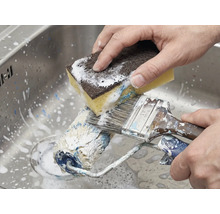 Rengöring av färgrulle och pensel med en svamp i diskhon.