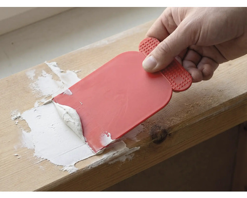 Hantverkare använder en spackel för att applicera fogmassa.