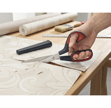 Tapetssax klipper tapeter på ett bord.