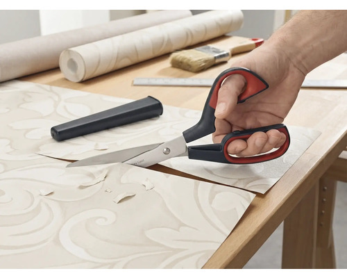 Tapetssax klipper tapeter på ett bord.
