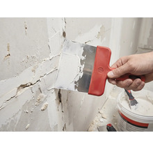 Hantverkare spacklar en vägg med en spackel