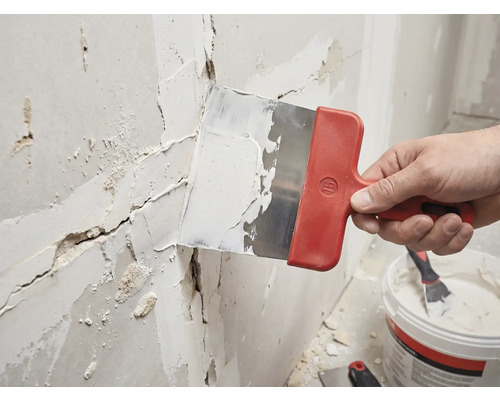 Hantverkare spacklar en vägg med en spackel