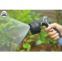 En hand håller i en trädgårdsspruta som sprutar vatten