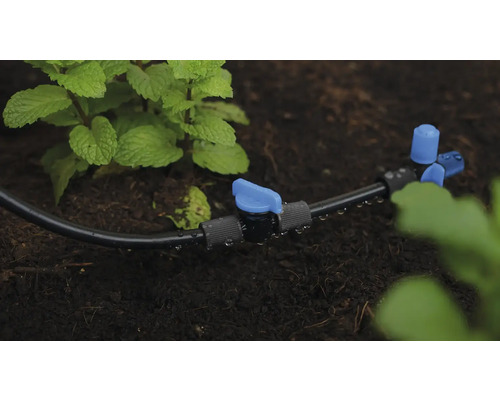 Bevattningssystem med droppslang och avstängningsventil i trädgårdsrabatten