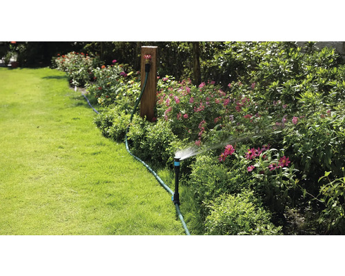 Trädgårdsbevattning med grässpridare i en blomstrande trädgård.