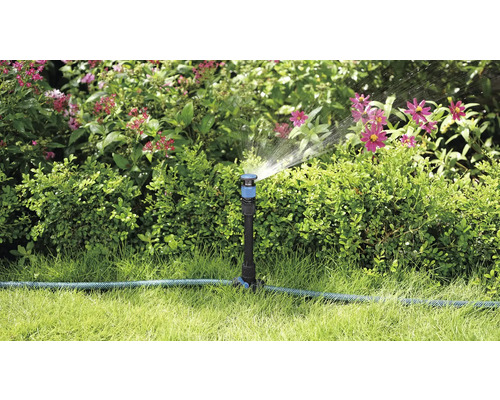 Trädgårdsscen med grässpridare som vattnar växter