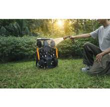 Man rengör en robotgräsklippare med en vattenslang i trädgården.