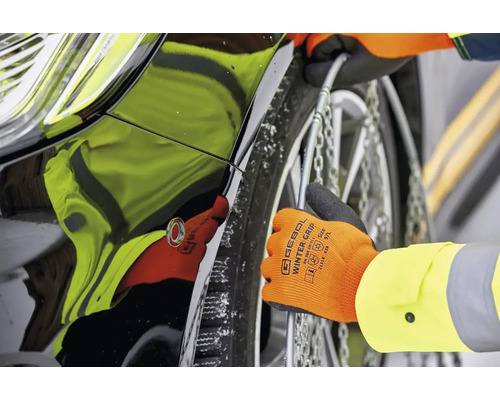 Montering av snökedjor på en bils däck med handskar.