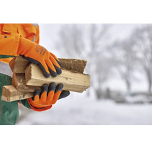 Person med arbetshandskar som bär vedträn