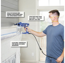 Man med skyddsmask använder färgsprutpistol för målningsarbeten inomhus