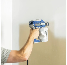 En person håller en färgsprutpistol framför en vägg