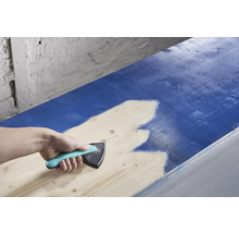 En person använder en färgfördelare för att applicera färg på trä