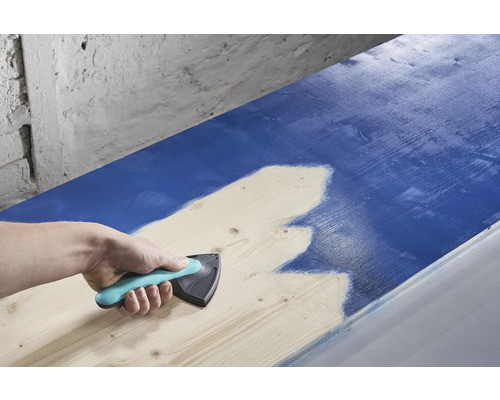 En person använder en färgfördelare för att applicera färg på trä