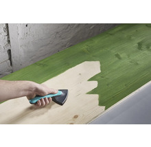 En träplanka målas med ett målarverktyg.