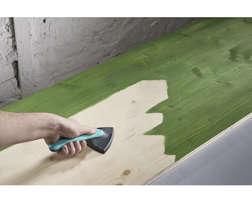 En träplanka målas med ett målarverktyg.