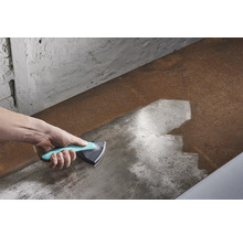 Hand med trekantsskrapa som rengör en metallyta