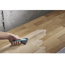 En person applicerar ytbehandling med en trekantig borste på en träskiva.