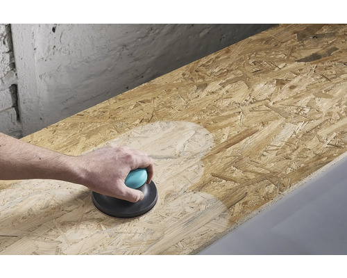 En person slipar en träskiva med en handhållen slipmaskin.