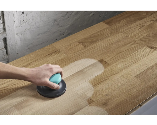 En person slipar en träskiva med en excenterslipmaskin.