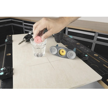 Scen av en arbetsbänk med borrmaskin, glas vatten och kakelborrverktyg