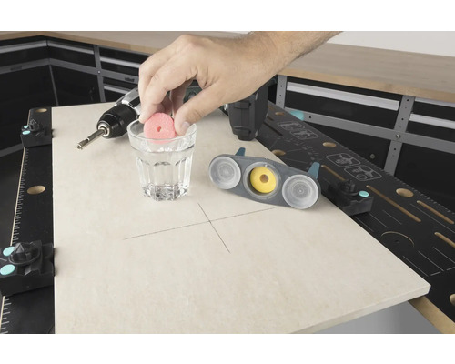 Scen av en arbetsbänk med borrmaskin, glas vatten och kakelborrverktyg