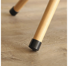 Detaljvy av ett stolsben med ett svart golvskydd på ett trägolv