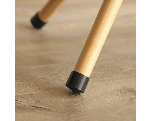 Detaljvy av ett stolsben med ett svart golvskydd på ett trägolv