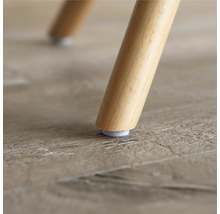 Närbild av ett trästolsben med filtdyna på ett trägolv