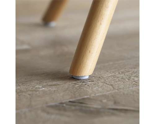 Närbild av ett trästolsben med filtdyna på ett trägolv