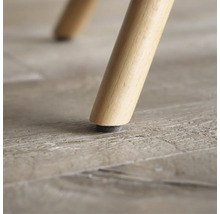 Närbild av ett möbelben i trä med golvskydd.