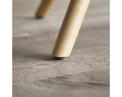 Närbild av ett möbelben i trä med golvskydd.